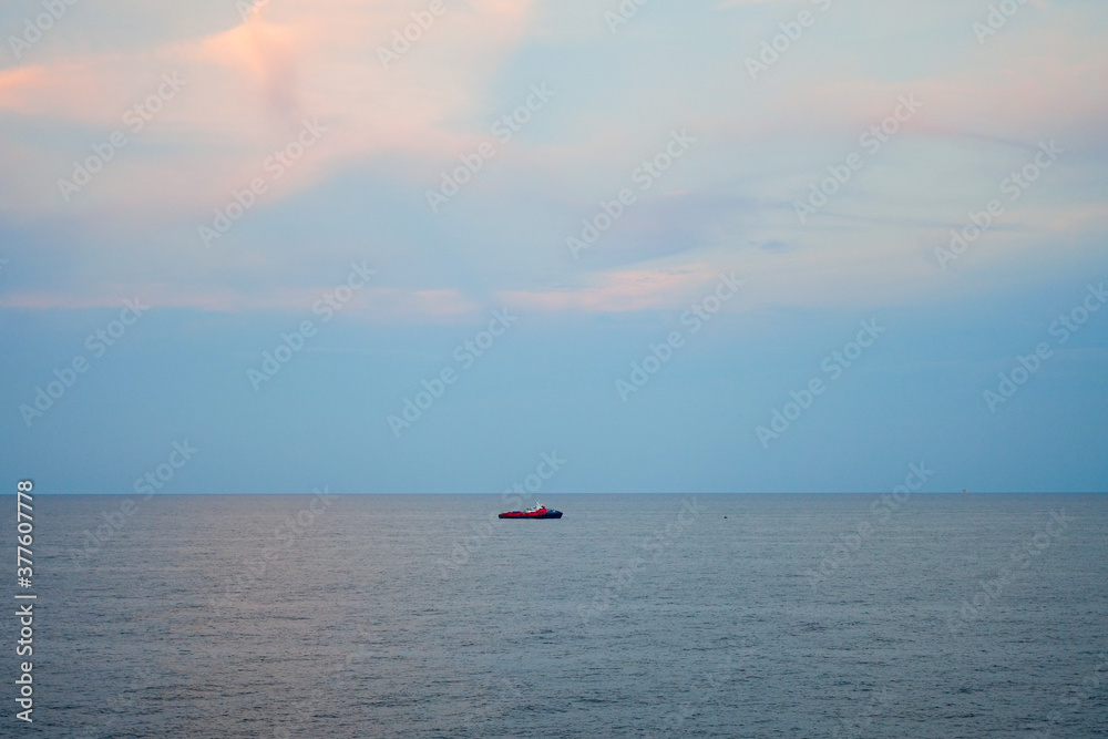 lonely sailing boat or crew boat in the sea with beautiful sky and cloud, minimal lonely concept.