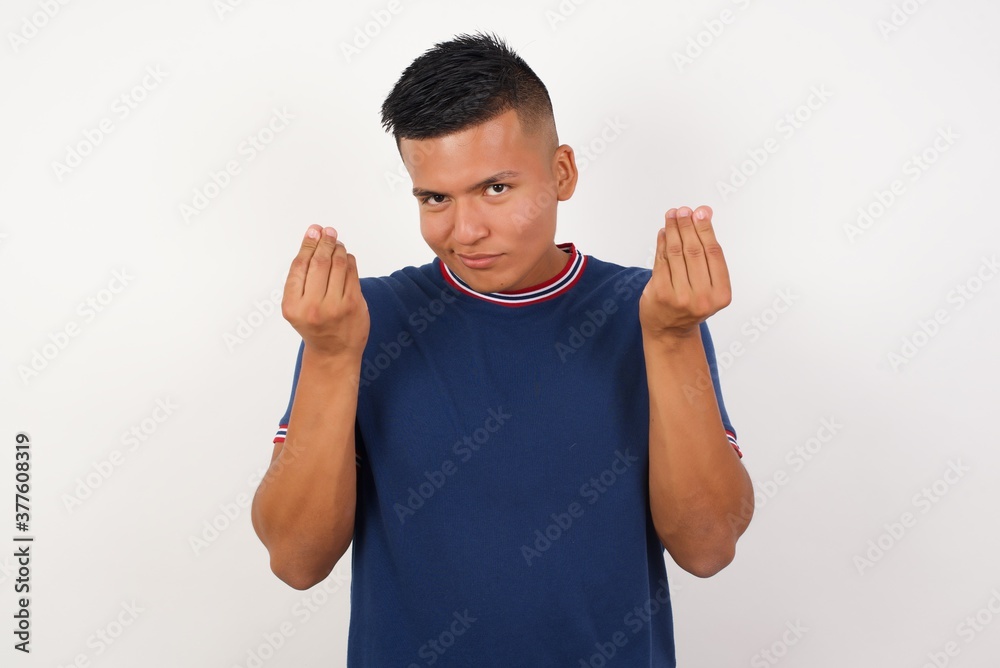 Young handsome hispanic man wearing casual t-shirt standing over white isolated background doing money gesture with hands, asking for salary payment, millionaire business Young handsome hispanic man wearing casual t-shirt standing over white isolated background doing money gesture with hands, asking for salary payment, millionaire business