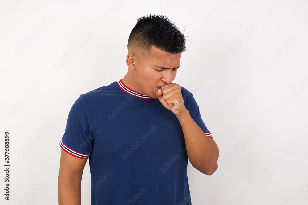 Young handsome hispanic man wearing casual t-shirt standing over white isolated background feeling unwell and coughing as symptom for cold or bronchitis. Healthcare concept. Young handsome hispanic man wearing casual t-shirt standing over white isolated background feeling unwell and coughing as symptom for cold or bronchitis. Healthcare concept.