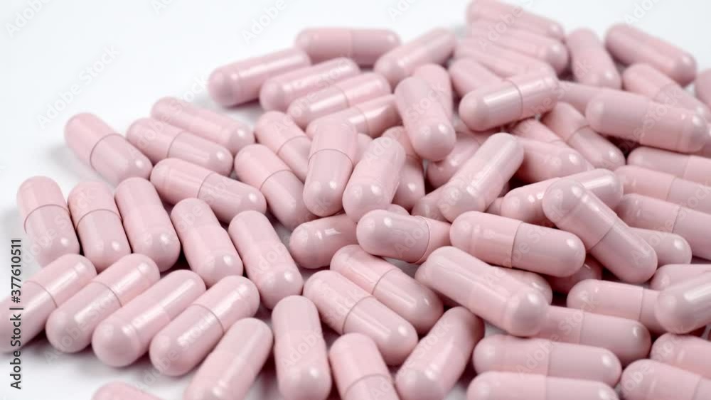 Close up of the rotation soft pink pills or capsules on white background Close up of the rotation soft pink pills or capsules on white background