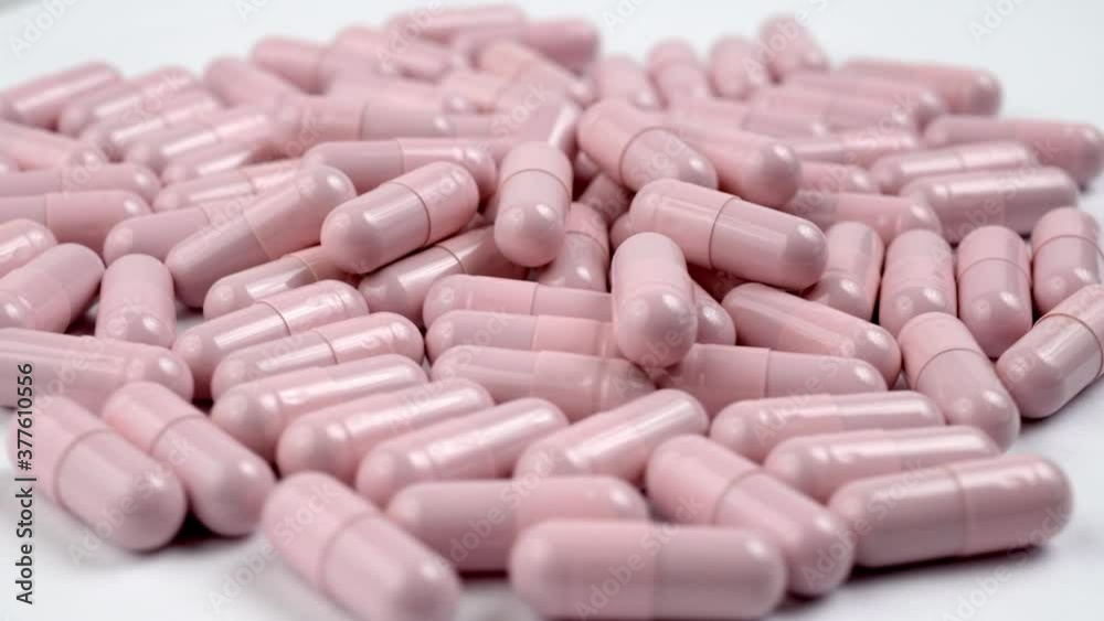 Close up of the rotation soft pink pills or capsules on white background Close up of the rotation soft pink pills or capsules on white background
