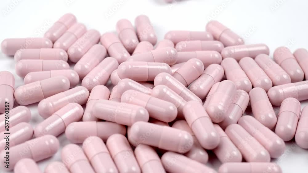 Close up of the rotation soft pink pills or capsules on white background Close up of the rotation soft pink pills or capsules on white background