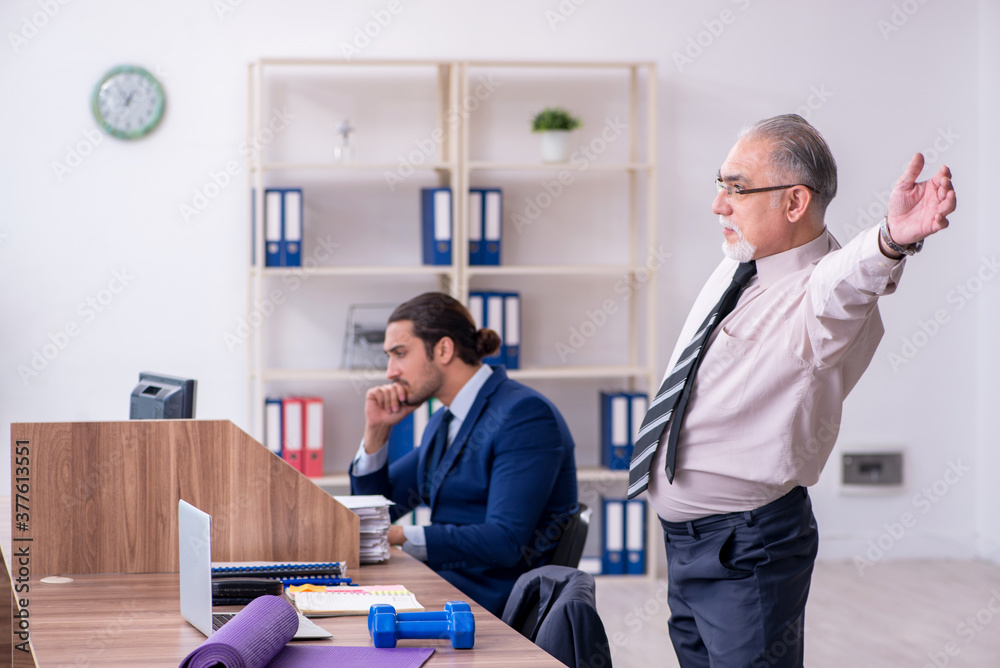 Two employees doing physical exercises at workplace Two employees doing physical exercises at workplace