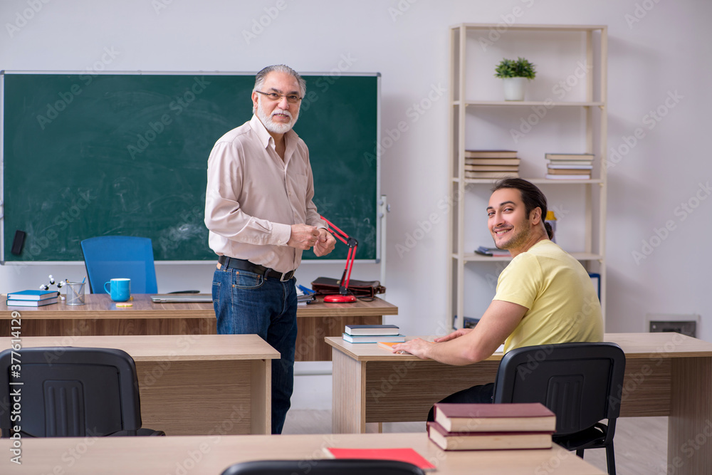 Old teacher and young male student in the classroom Old teacher and young male student in the classroom