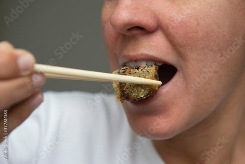 Close up of woman's mouth eating delicious salmon sushi (Hot roll).