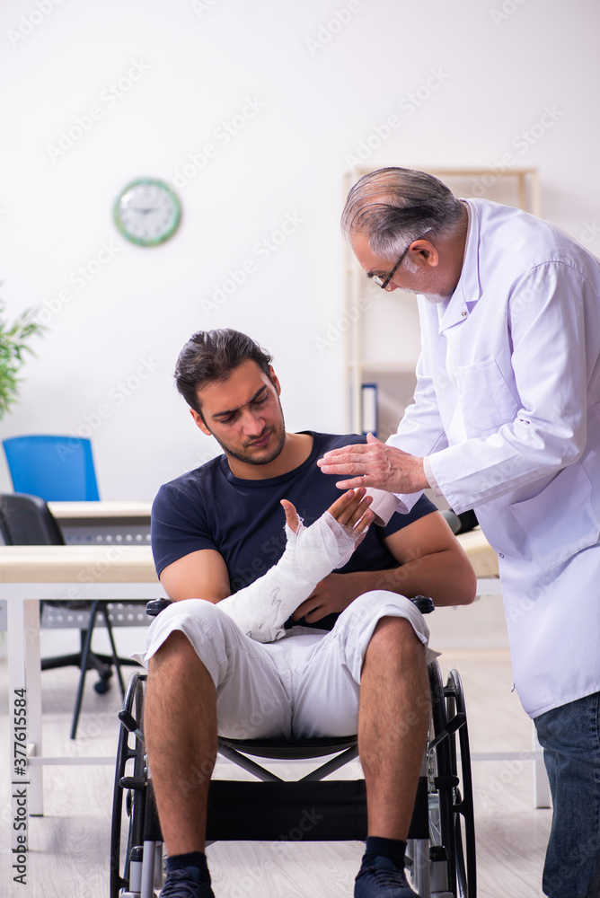 Obraz premium Young injured man visiting experienced male doctor traumatologis