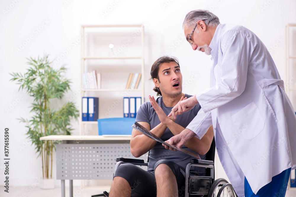 Young male patient in wheel-chair visiting old doctor radiologis Young male patient in wheel-chair visiting old doctor radiologis