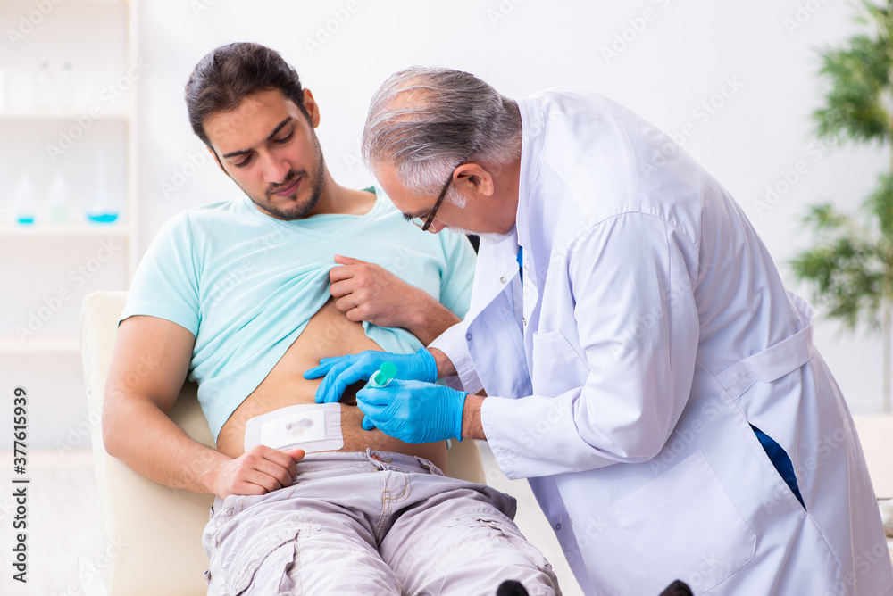 Fototapeta premium Injured young man visiting experienced male doctor