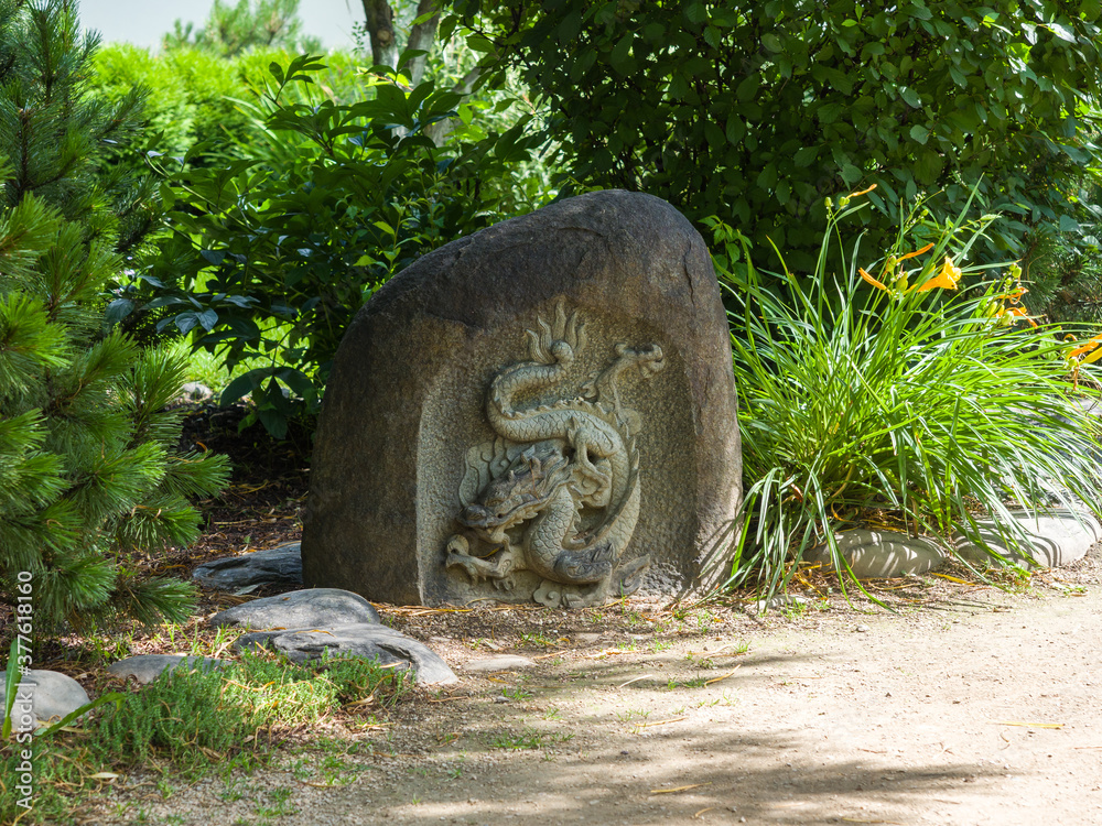 Japanese stone sculpture dragon bas-relief. Landscaping. Summer sunny day