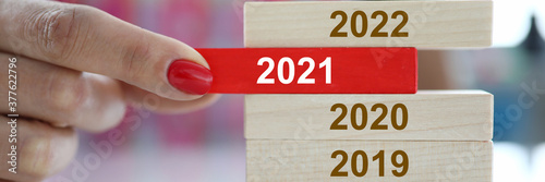 Female hand hold red wooden block with 2021 sign closeup. Chops and changes concept photo