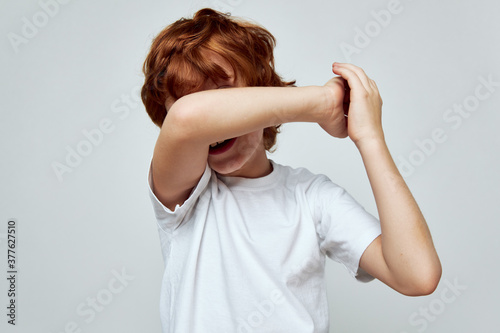 Fényképezés redhead boy covers hand over face white t-shirt cropped view studio