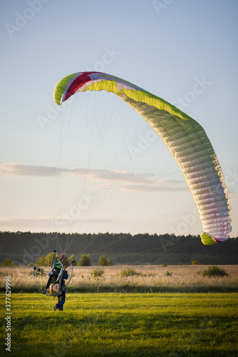 A pilot with a petrol powered backpack landed and folds the wing. Flying with a motorized wing. Extreme sports. Paralet and small aircraft.