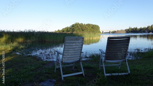 two plastic chairs by the lake on a summer afternoon