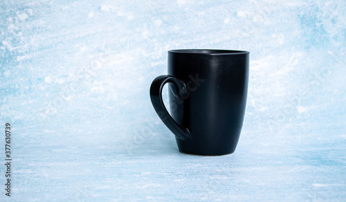 Black cup for coffee on a blue background. side view