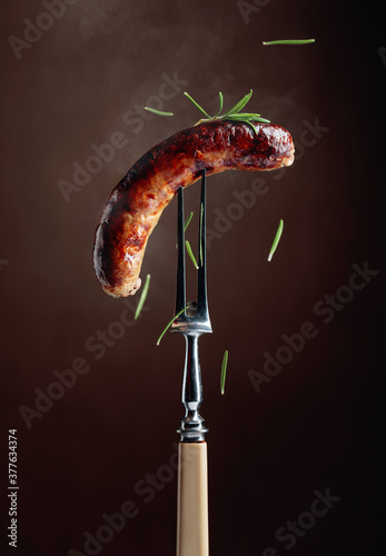 Hot sausage on a fork sprinkled with rosemary.