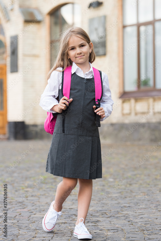 Little child in formal uniform dress go to school carrying bag, back to school