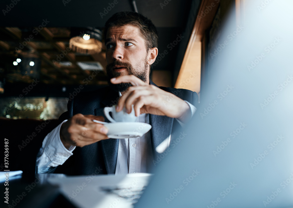 Business man sitting in a cafe with a cup of coffee in his hands in front of a laptop technology communication Business man sitting in a cafe with a cup of coffee in his hands in front of a laptop technology communication