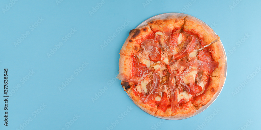 Whole Italian pizza with cheese and mushrooms on a metal tray over bright blue pastel bakcground. Whole Italian pizza with cheese and mushrooms on a metal tray over bright blue pastel bakcground.