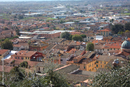 the red roofs of the inhabited houses, the church and the bell tower of the pietrasanta cathedral seen from the green of a hill at the top