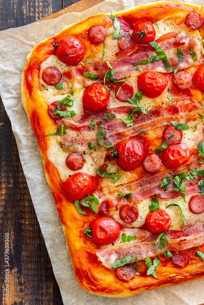 Pizza with bacon, sausage, mozzarella, tomatoes and basil. Italian cuisine. Recipe.