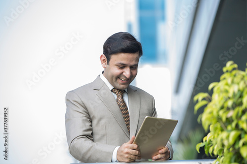 Indian businessman using digital tablet on the way to work