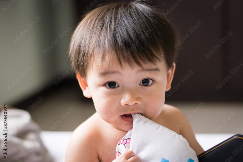 Little asian boy gnawing his pillow Little asian boy gnawing his pillow