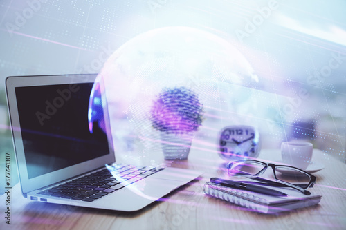 Computer on desktop in office with technology theme hologram. Double exposure. Tech concept.