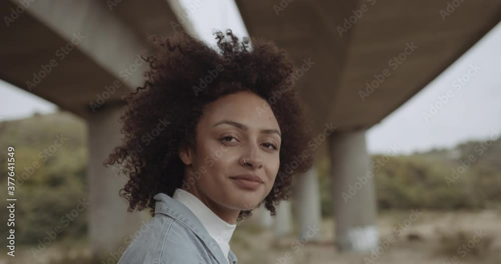 Portrait of African American woman looking at camera, young cool trendy black female in urban city background with afro hairstyle