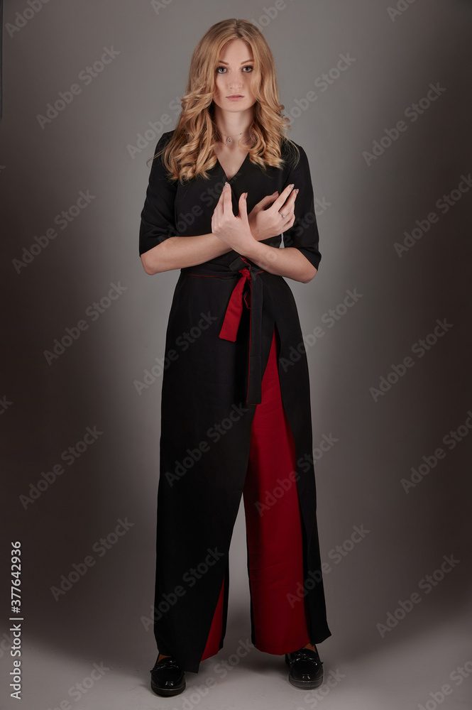 Fototapeta premium A slender girl in black and red clothes on a gray background.