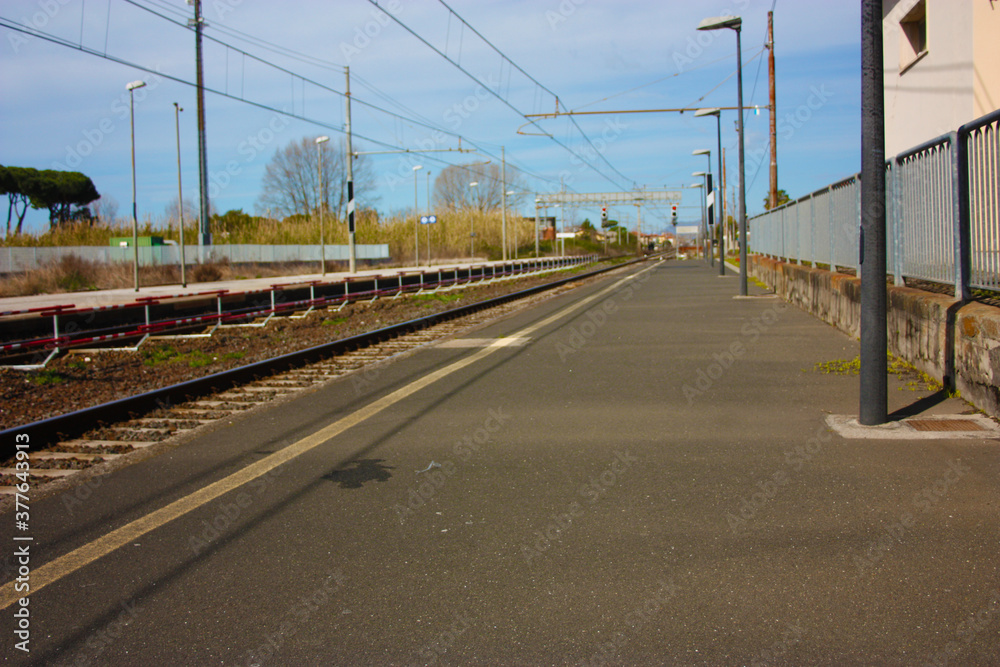 a small deserted local station during the day. sidewalk for waiting passengers waiting for trains for their journeys, between departures and arrivals
