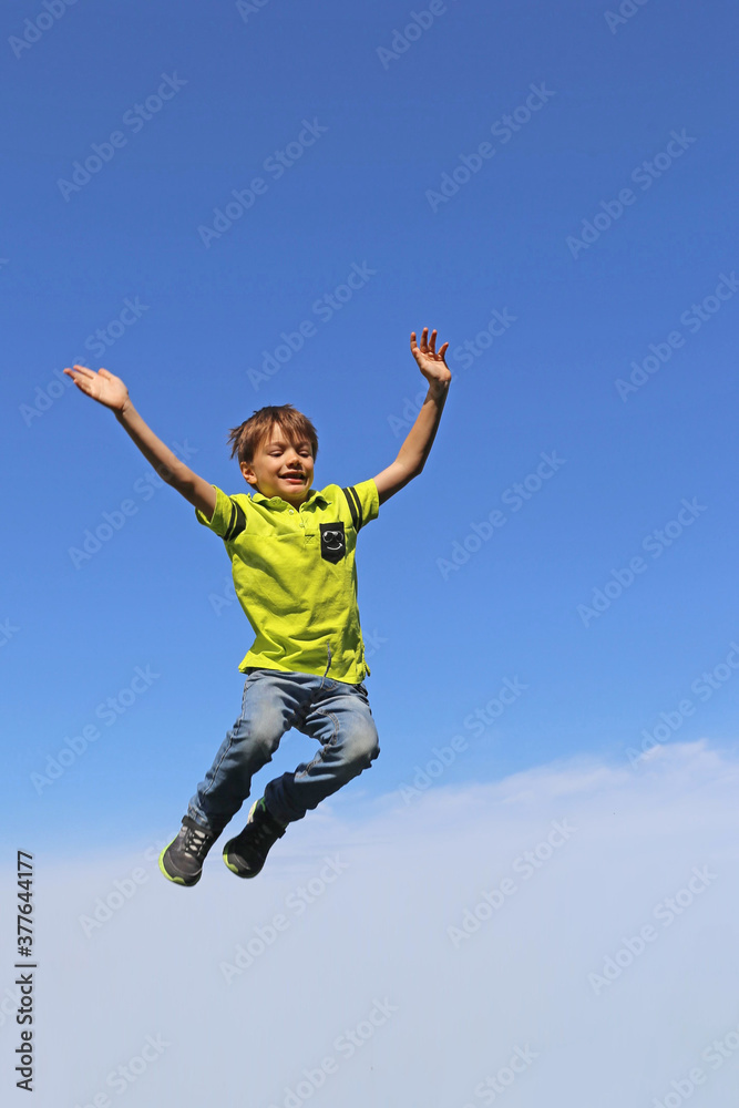 Junge springt in die Luft, im Hintergrund blauer Himmel Junge springt in die Luft, im Hintergrund blauer Himmel