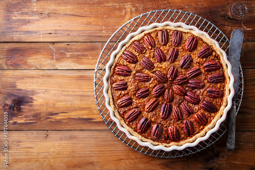 Pecan pie, cake on a cooling rack. Brown background. Copy space. Top view.