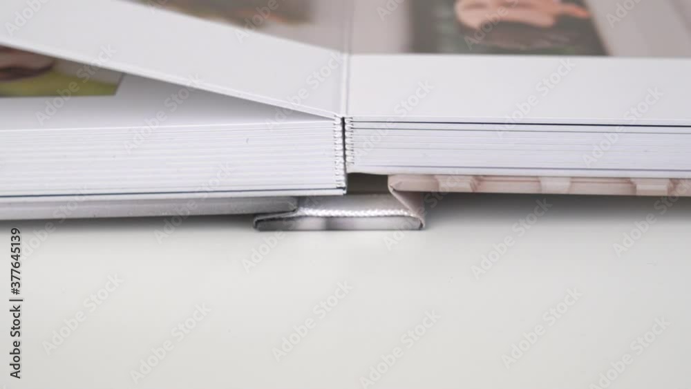 close up. flipping through wedding photo book over on table.