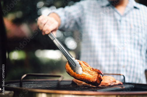 Man hand grilling barbecue on fire at backyard on day