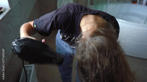 girl dries her hair with a hair dryer in the bathroom