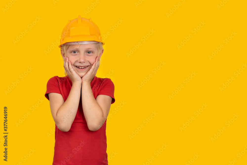 Joyful blond boy in hard hat on yellow background. Choice of specialty