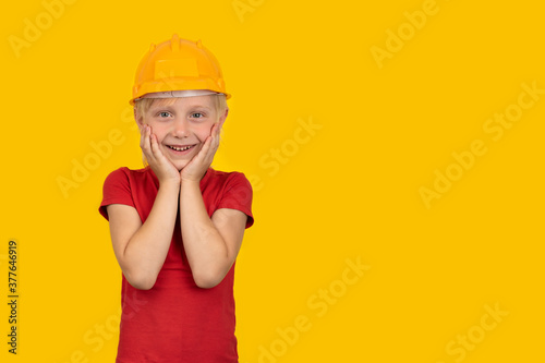 Joyful blond boy in hard hat on yellow background. Choice of specialty