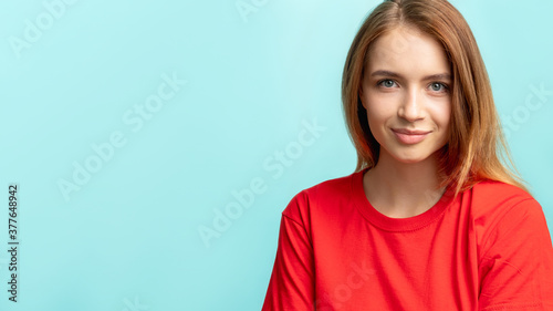 Confident woman portrait. Commercial background. Ambitious lady in red with nude makeup looking at camera smiling isolated on blue copy space. Success individuality.
