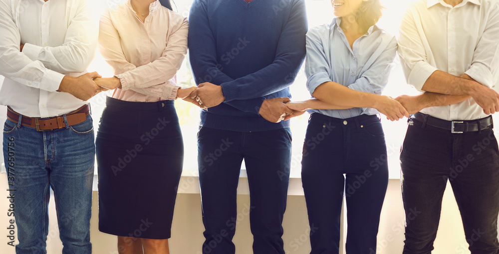 © Studio Romantic - Positive office employees standing in a row holding hands supporting each other © Studio Romantic - Positive office employees standing in a row holding hands supporting each other
