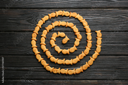 Delicious goldfish crackers on black wooden table, flat lay