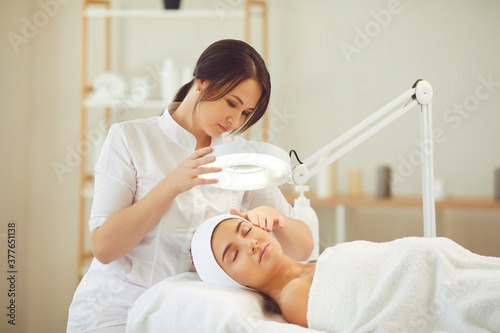 Relaxed young woman enjoying professional skincare procedures in modern beauty salon photo