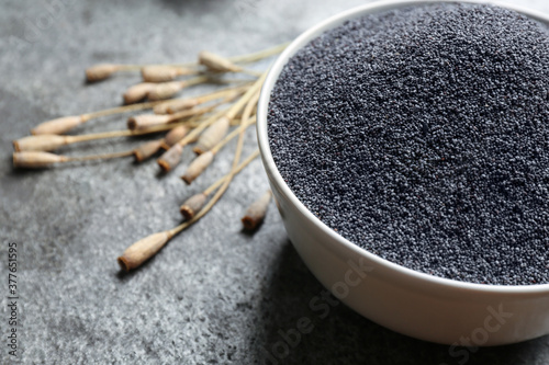 Poppy seeds in bowl on grey table, closeup. Space for text