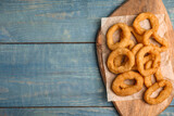 Fried onion rings served on blue wooden table, top view. Space for text
