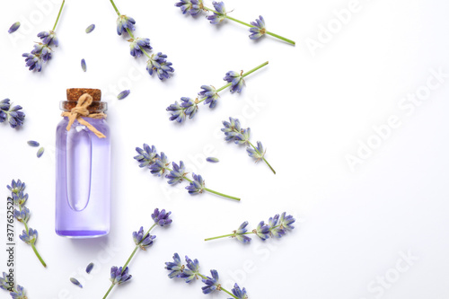 Composition with lavender flowers and natural essential oil on white background, top view