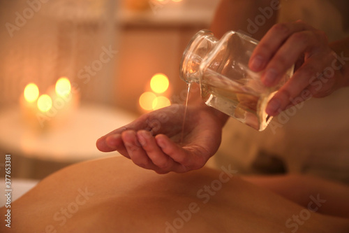 Young woman receiving back massage with oil in spa salon, closeup