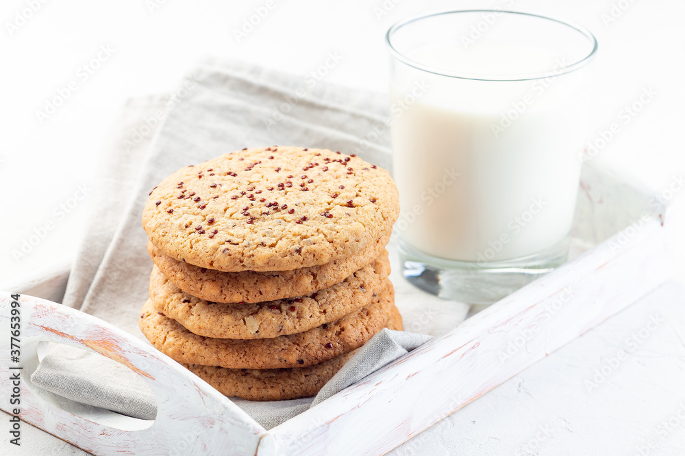 Oatmeal and red quinoa cookies with a glass of milk, on wooden tray, horizontal Oatmeal and red quinoa cookies with a glass of milk, on wooden tray, horizontal