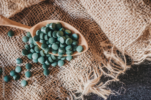 A close-up image of a spoon with spirulina on a burlap background. Super food. Vegan food. Seaweed.