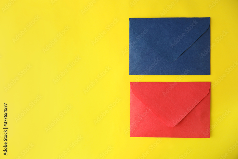 Fototapeta premium Colorful paper envelopes on yellow background, flat lay. Space for text