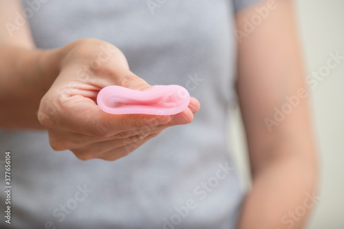 Close up of woman hand folding menstrual cup showing how to use. Women health concept, zero waste alternatives