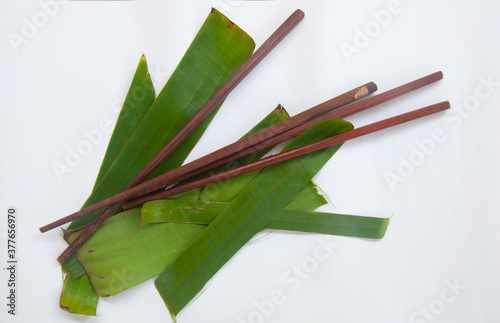 Two wooden chopsticks put on banana leaf